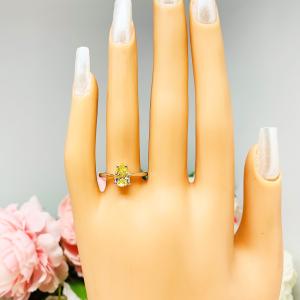Mannequin hand with long white shimmery nails, displayed against a soft white-gray background with pink and white floral accents. The hand is wearing a sterling silver engagement ring set with a 9x6mm pear-cut canary yellow cz.