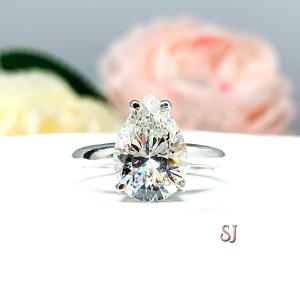 An elegant 4-prong sterling silver engagement ring with a 3mm wide band featuring a 13x9mm near colorless precision-cut pear cubic zirconia. Displayed on a white surface with a floral background.