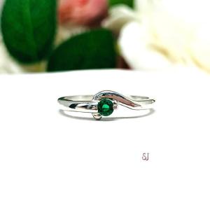 A sterling silver round gemstone bypass ring with a thin band. The ring is set with 3mm round lab emerald. The modern setting design curves around the gemstone. The ring is facing toward the back and is set against a white background.
