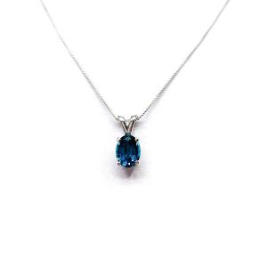 Close‑up of an oval‑cut teal blue lab gemstone sterling silver pendant suspended from a delicate silver chain. The pendant is the focal point, set against a white background.