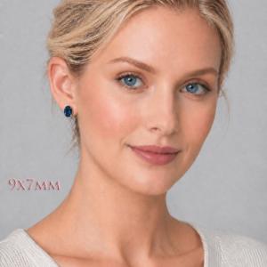 A woman wearing 9x7mm oval lab blue sapphire oval sterling silver stud earrings. Model image for size and styling reference — not a photo of the actual earrings.