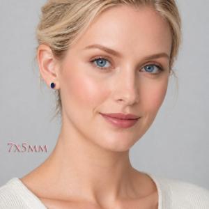 A woman wearing 7x5mm oval lab blue sapphire oval sterling silver stud earrings. Model image for size and styling reference — not a photo of the actual earrings.