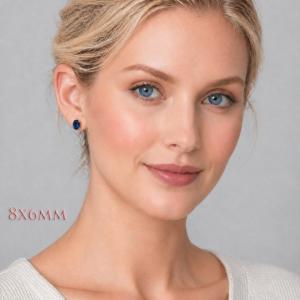 A woman wearing 8x6mm oval lab blue sapphire oval sterling silver stud earrings. Model image for size and styling reference — not a photo of the actual earrings.
