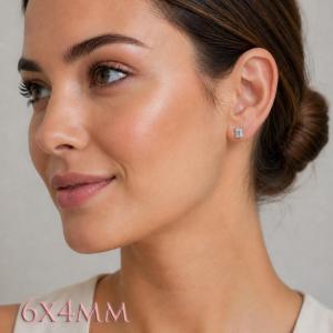 A woman wearing silver earrings set with 6x4mm emerald cut natural white topaz gemstones. Model image for size and styling reference — not a photo of the actual earrings.