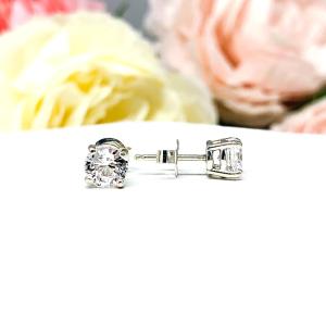 A pair of sterling silver 4-prong basket stud earrings set with round mixed brilliant lab white sapphires, displayed with one earring facing the front to showcase the faceting and one facing to the side to display center post and the butterfly friction clasp. The earrings are shown on a white background.