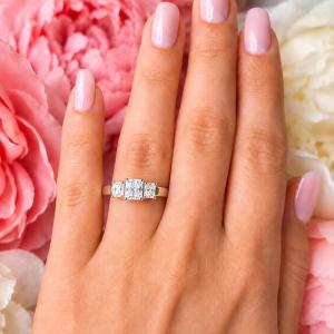A woman's hand wearing a sterling silver 3-stone engagement ring featuring an 8x6mm radiant cut cubic zirconia center stone with two smaller radiant CZ side stones. The highly polished wide band tapers for comfort. Model image for size and styling reference — not a photo of the actual ring.