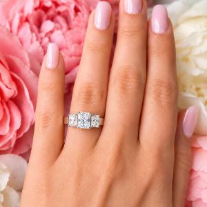 A woman's hand wearing a sterling silver 3-stone engagement ring featuring an 9x7mm radiant cut cubic zirconia center stone with two smaller radiant CZ side stones. The highly polished wide band tapers for comfort. Model image for size and styling reference — not a photo of the actual ring.