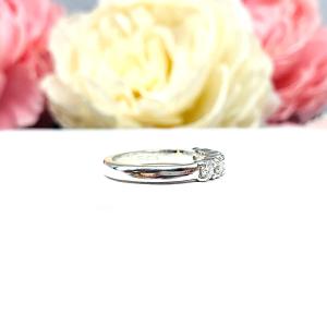 Sterling silver stackable 5-stone wedding band featuring 3mm round authentic moissanite stones in prong settings, displayed against a soft floral background.