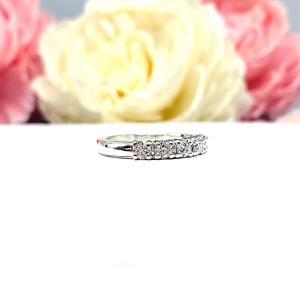 Sterling silver stackable 5-stone wedding band featuring 3mm round authentic moissanite stones in prong settings, displayed against a soft floral background.