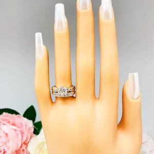 Mannequin hand with long white shimmery nails, displayed against a soft white-gray background with pink and white floral accents. The hand is wearing a sterling silver stackable 5-stone wedding band featuring 3mm round authentic moissanite stones in prong settings. The band is shown with a round moissanite engagement ring with leaf design. Engagement ring not included.