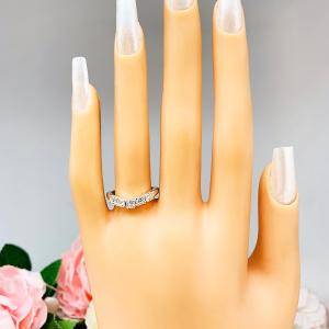 Mannequin hand with long white shimmery nails, displayed against a soft white-gray background with pink and white floral accents. The hand is wearing a sterling silver 5-stone curved wedding band featuring 3mm round precision faceted moissanite stones in prong settings.