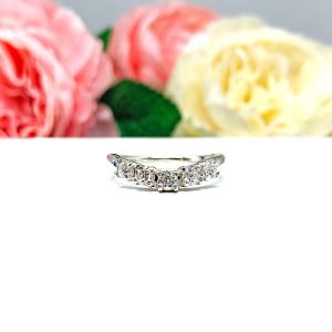 Sterling silver 5-stone curved wedding band featuring 3mm round precision faceted moissanite stones in prong settings, displayed against a soft floral background.