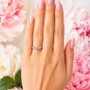 Sterling silver curved band set with 3mm round moissanites shown worn on a woman's hand.