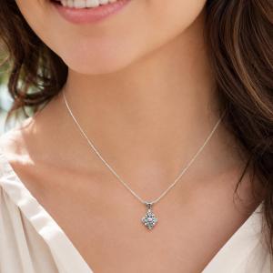 A woman wearing a sterling silver cluster pendant featuring four 3mm round light blue aquamarine gemstones and an elegant twist design bail. Suspended from a delicate sterling silver chain. Model image for size and styling reference — not a photo of the actual necklace.