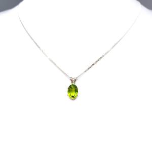Bright neon green 9×7 mm oval apatite gemstone in a sterling silver six‑prong pendant, suspended from a delicate chain and displayed on a white background.