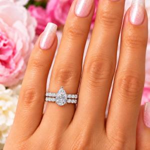 A woman's hand wearing an elegant sterling silver engagement ring set featuring a 10x7mm precision-cut pear cubic zirconia with pave CZ accents in a half eternity band. Shown with optional matching half-eternity band, designed to nest seamlessly. Model image for size and styling reference — not a photo of the actual ring.
