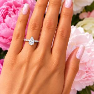 A woman's hand wearing an elegant sterling silver engagement ring set featuring a 9x6mm precision-cut pear cubic zirconia with pave CZ accents in a half eternity band. Model image for size and styling reference — not a photo of the actual ring.