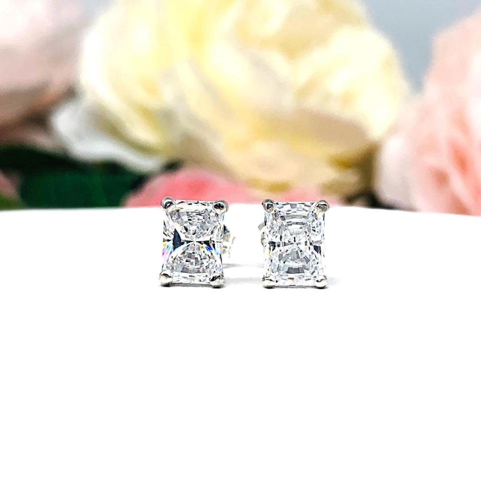 A pair of silver stud earrings with "crushed ice" rectangular radiant cut clear cubic zirconia stones. The basket style earrings are on a white surface. Both earrings are facing forward showcasing the dazzling sparkle of the czs.