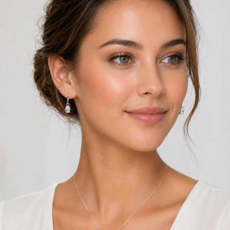 Woman wearing colorless oval cz dangle earrings and pendant necklace (sold separately). Model image for size and styling reference — not a photo of the actual earrings.