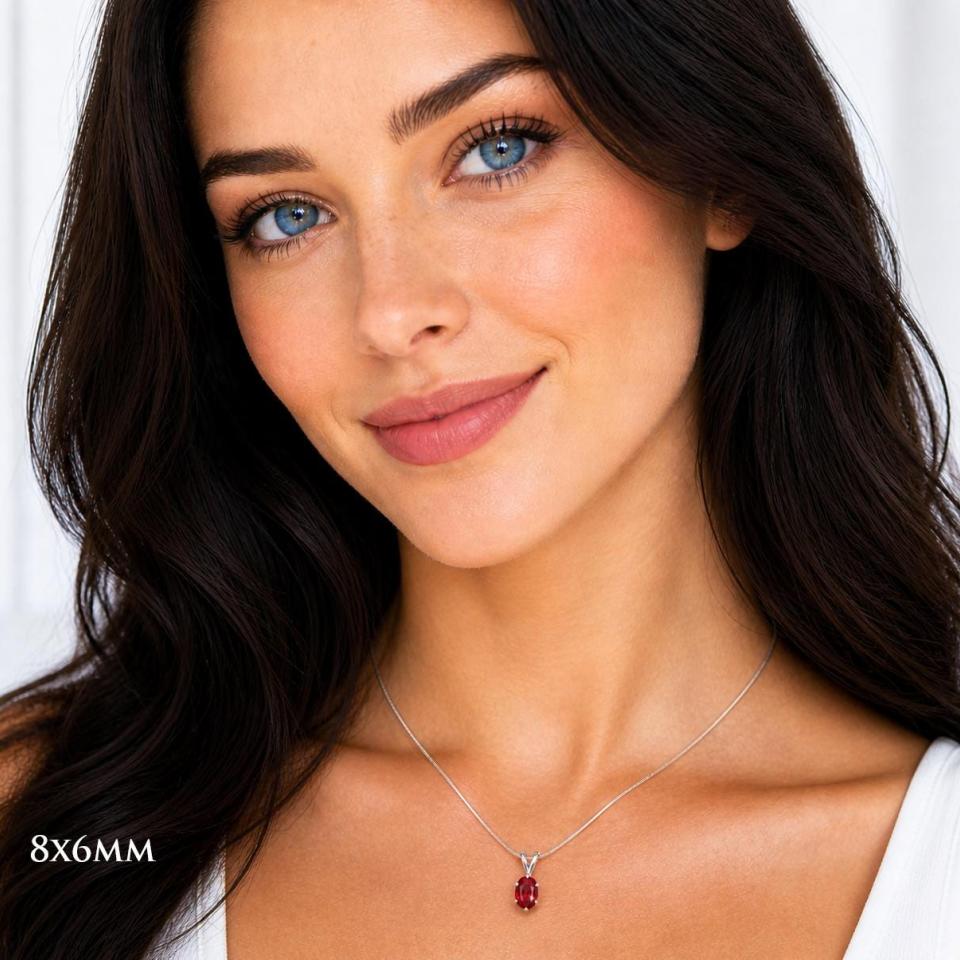 A woman wearing an 8x6mm oval lab ruby sterling silver 6-prong pendant necklace. Model image for size and styling reference — not a photo of the actual necklace.
