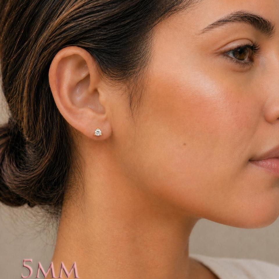 A woman wearing 5mm round 3-prong martini moissanite stud earrings. martini three prong moissanite stud earrings. Model image for size and styling reference — not a photo of the actual earrings.