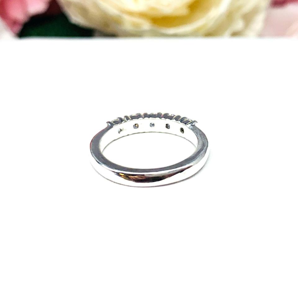 Sterling silver stackable 5-stone wedding band featuring 3mm round authentic moissanite stones in prong settings, displayed against a soft floral background.