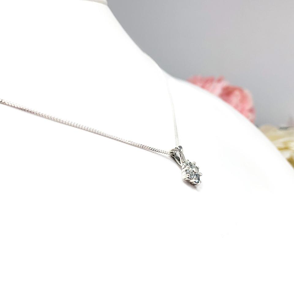 Sterling silver cluster pendant featuring four 3mm round light blue aquamarine gemstones and an elegant twist design bail. Suspended from a delicate sterling silver chain and set against a white background.