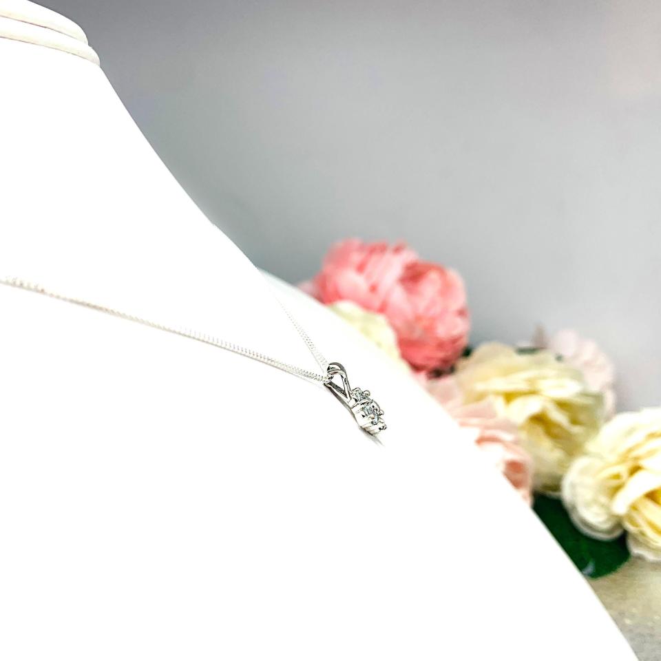 Sterling silver cluster pendant featuring four 3mm round light blue aquamarine gemstones and an elegant twist design bail. Suspended from a delicate sterling silver chain and set against a white background.