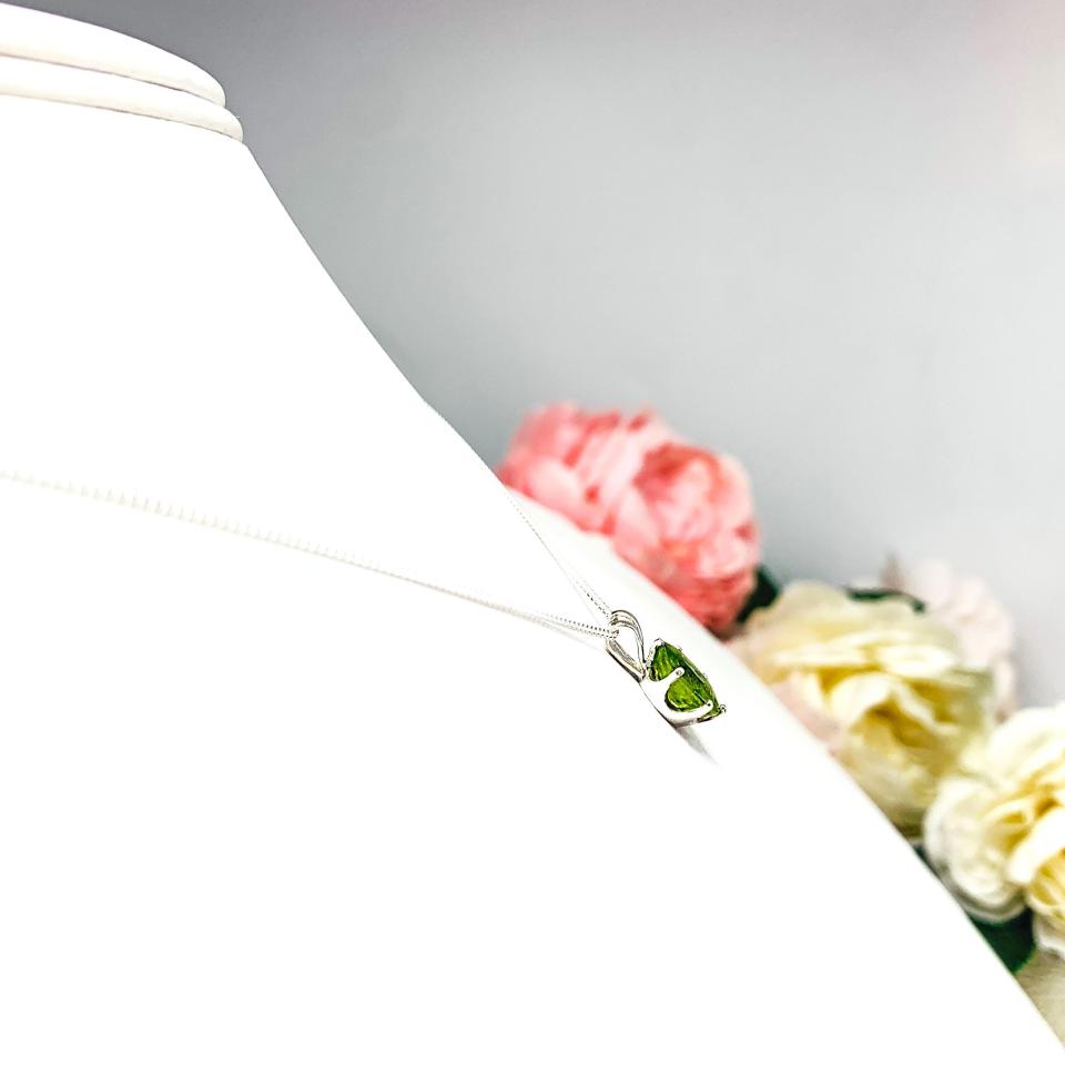 Bright neon green 9×7 mm oval apatite gemstone in a sterling silver six‑prong pendant, suspended from a delicate chain and displayed on a white background.