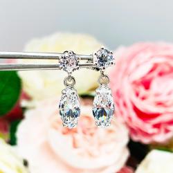A pair of silver drop earrings with marquise cut clear cubic zirconia stones. The top 6-prong stud earrings have a smaller round cubic zirconia stone at the top of the drop.