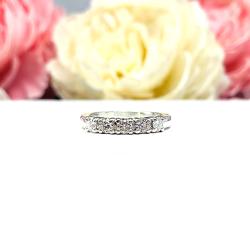 Sterling silver stackable 5-stone wedding band featuring 3mm round authentic moissanite stones in prong settings, displayed against a soft floral background.