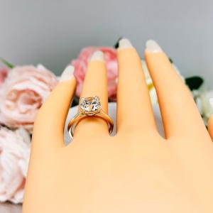 Mannequin hand with long white shimmery nails, displayed against a soft white-gray background with pink and white floral accents. The hand is wearing a sterling silver split-prong cathedral engagement ring set with a near colorless old mine cut cubic zirconia.