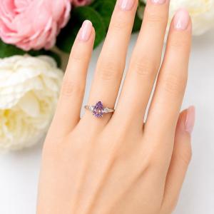 A woman's hand wearing a stunning sterling silver ring with a pear‑cut Rose de France amethyst and round rainbow moonstones. Model image for size and styling reference — not a photo of the actual ring.