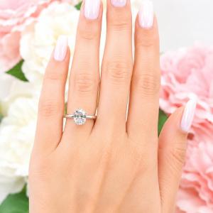 A woman's hand wearing a sterling silver ring with a 9x7mm oval lab created white sapphire set in a 6-prong setting. Model image for size and styling reference — not a photo of the actual ring.