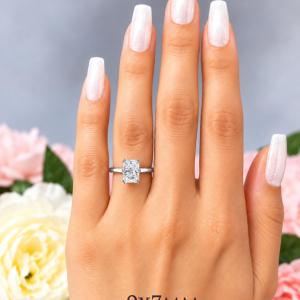 A woman's hand wearing a sterling silver double-prong 9x7mm radiant-cut cubic zirconia solitaire engagement ring. Model image for size and styling reference — not a photo of the actual ring.