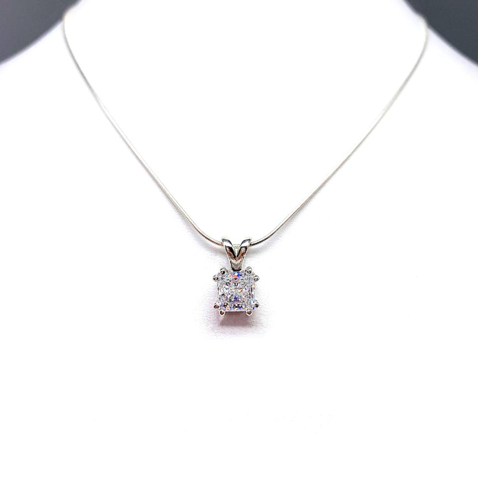 A sparkling princess cut cz in a double prong sterling silver setting, suspended from a delicate chain. The necklace is set against a white background.
