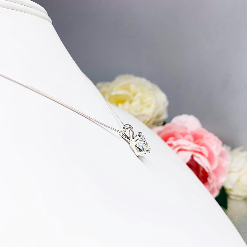 A sparkling princess cut cz in a double prong sterling silver setting, suspended from a delicate chain. The necklace is set against a white background.