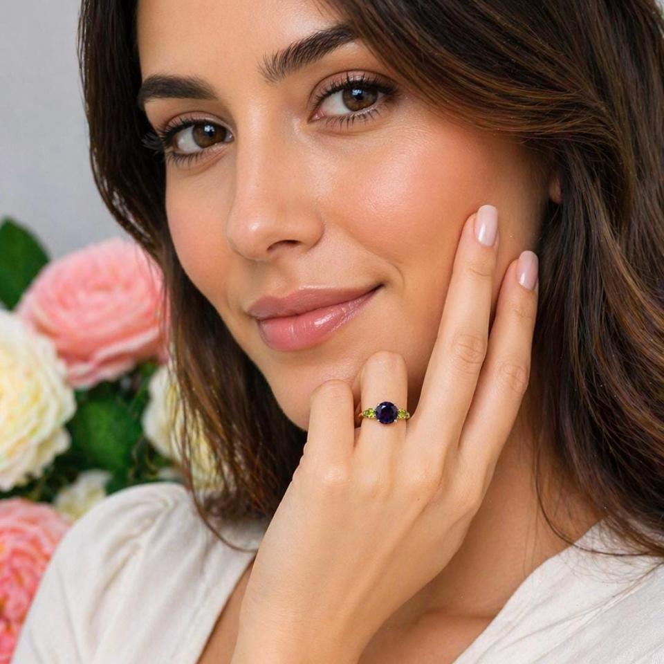 Sterling silver ring featuring a round-cut deep purple African amethyst flanked by two bright green pear-cut Arizona peridots, shown worn on the hand of a woman. Model image for size and styling reference — not a photo of the actual ring