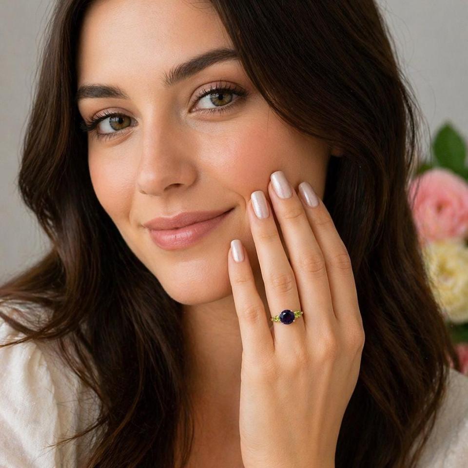 Sterling silver ring featuring a round-cut deep purple African amethyst flanked by two bright green pear-cut Arizona peridots, shown worn on the hand of a woman. Model image for size and styling reference — not a photo of the actual ring
