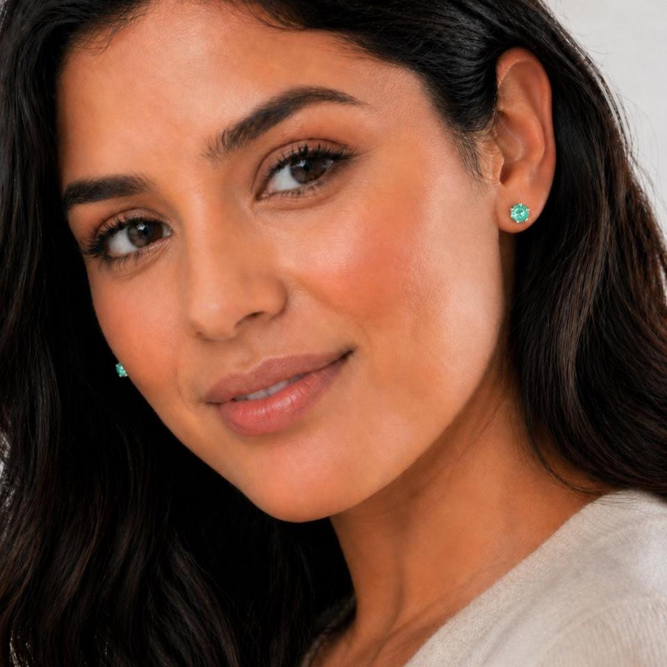 A woman wearing silver 6 prong earrings set with 6mm round sea foam green lab spinels. Model image for size and styling reference — not a photo of the actual earrings.